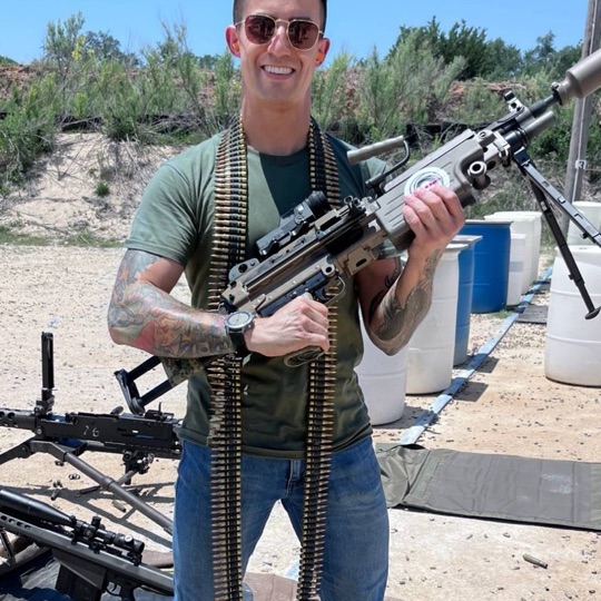 Guest holding a belt-fed machine gun on the range
